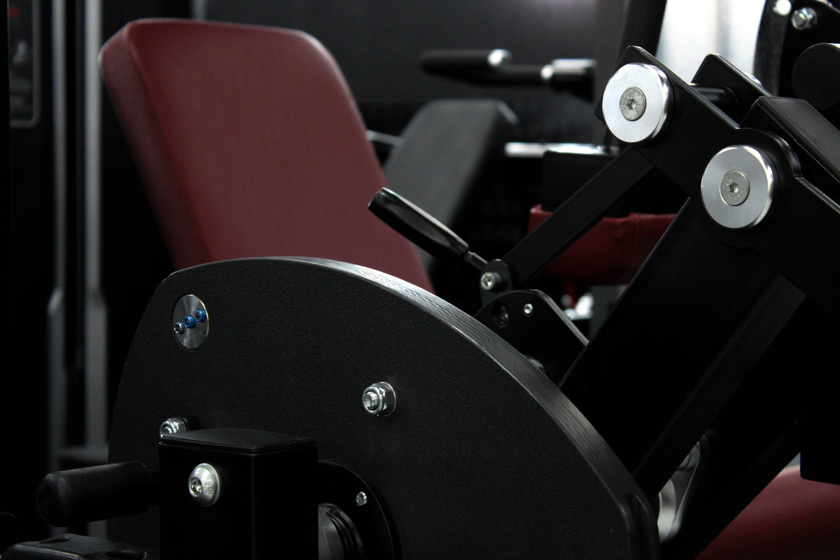 Reload Leg Curl machine - matte black frame red seat in commercial gym