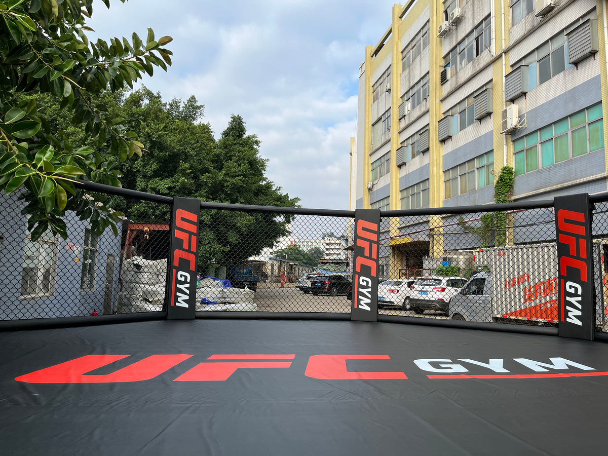 Competition‑standard elevated MMA cage showing platform height and corner pads