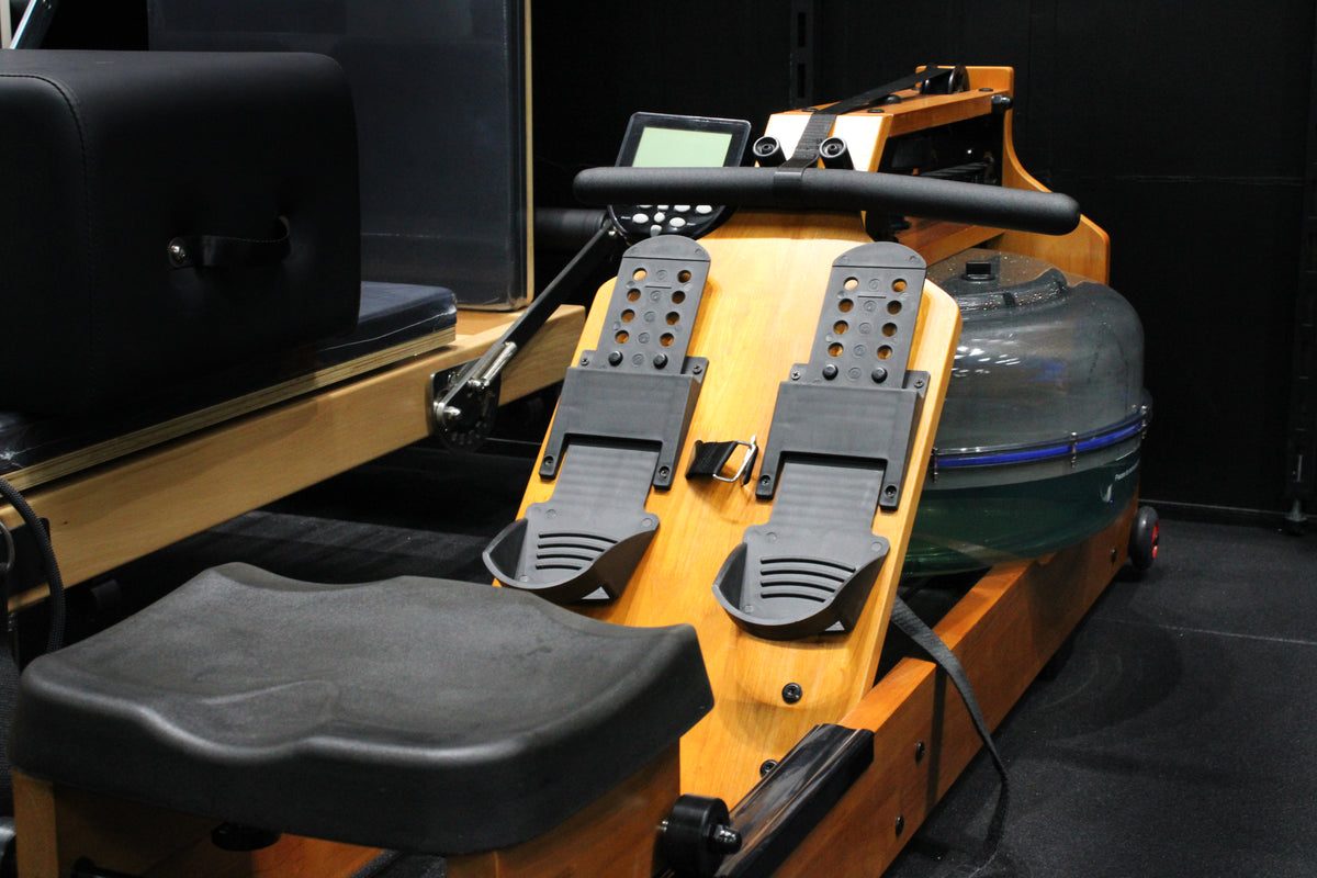 Reload Water Rower on gym floor showing ergonomic seat, dual rails, and LCD console