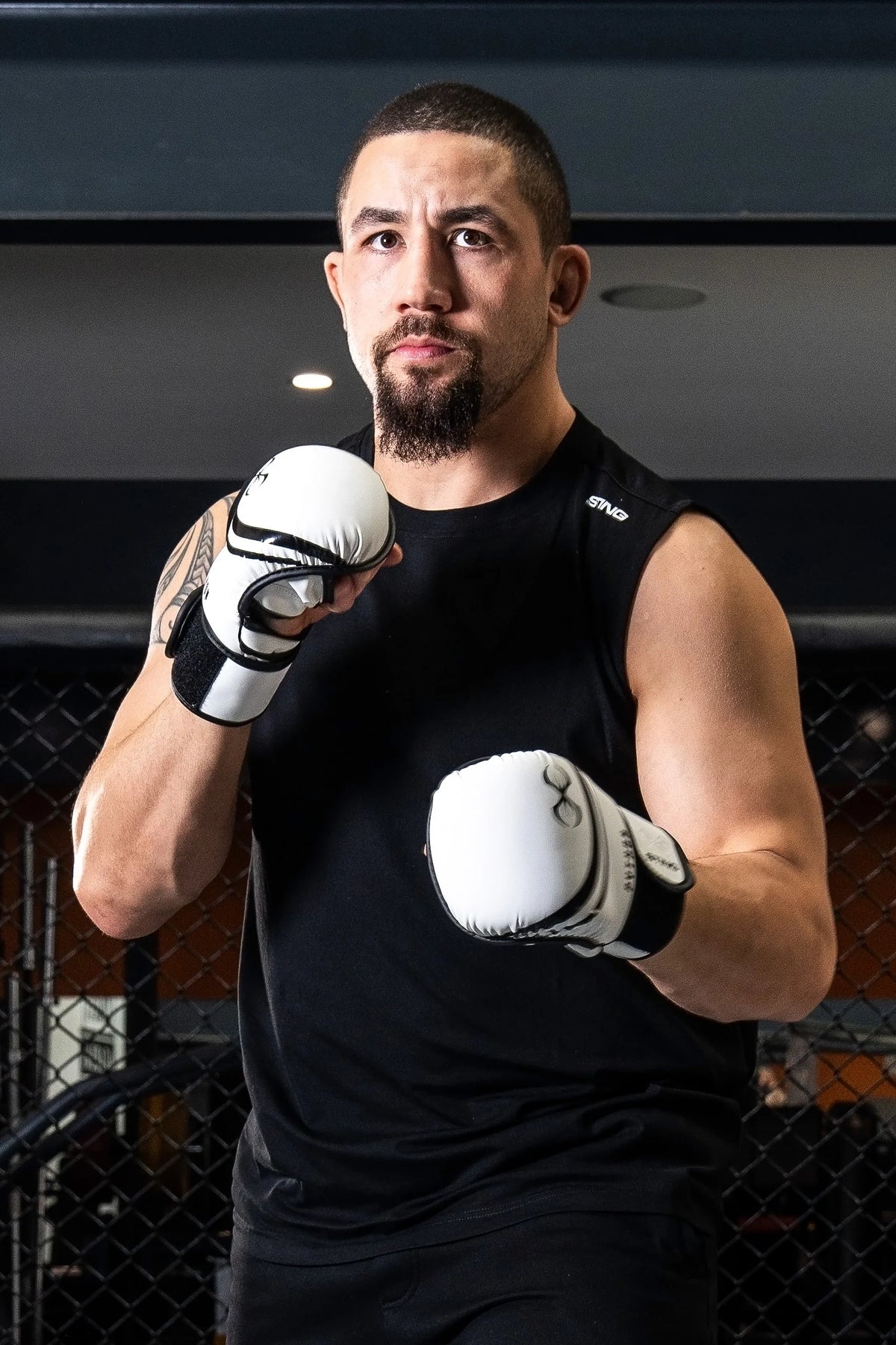 Man in black athletic wear with white boxing gloves in a fighting stance.