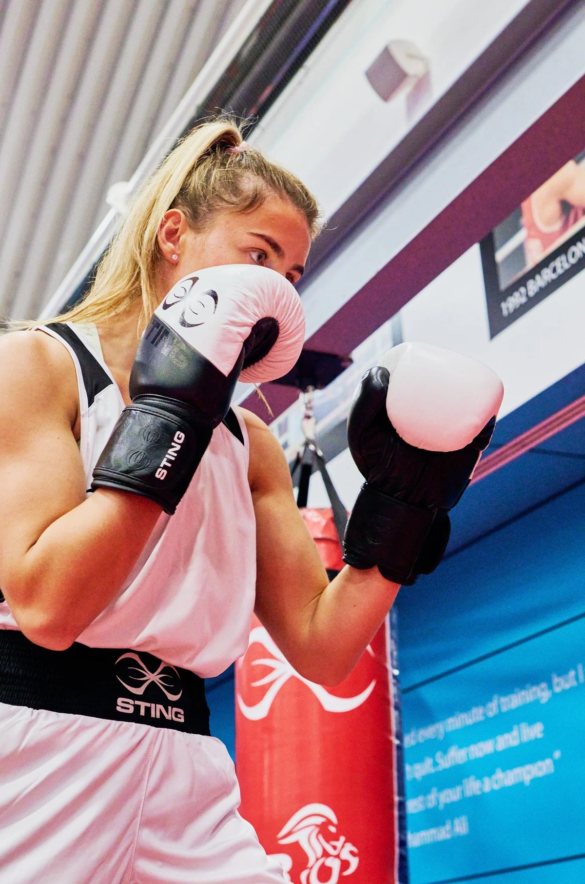 Woman in sting boxing gloves training with a sting punching bag indoors