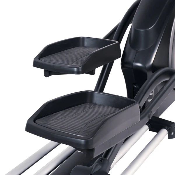 Close-up of a black exercise bike with foot platforms on a white background